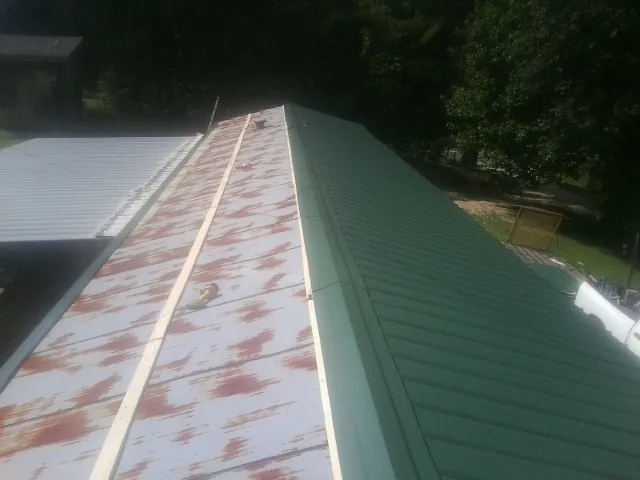 Old rusted panels beside newly installed green metal roofing — Wind Damage Roof Repair by Roofing Brothers in Nehawka