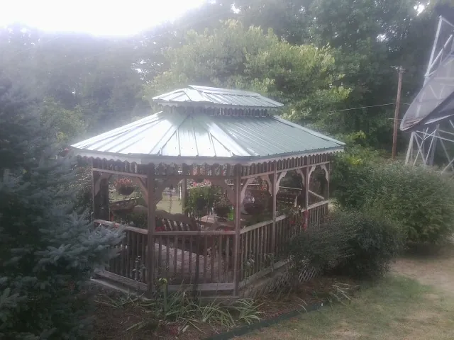 Green metal roof on a backyard gazebo surrounded by garden beds in Nehawka