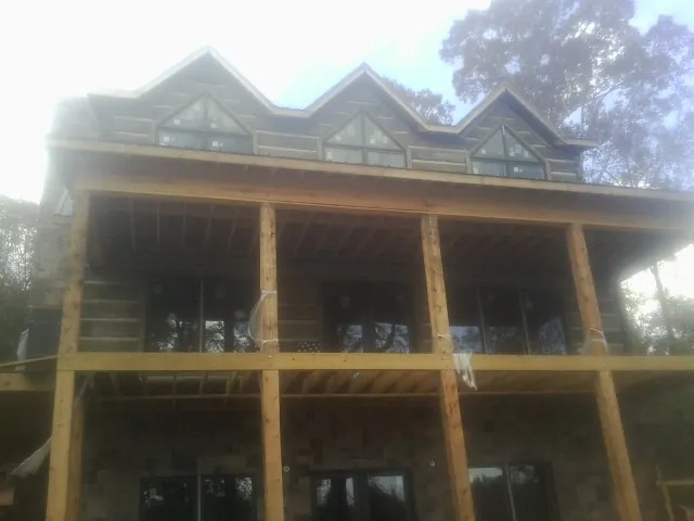 Dormers and porch framing on a large log home under construction — Roof Coating work by our crew in Nehawka