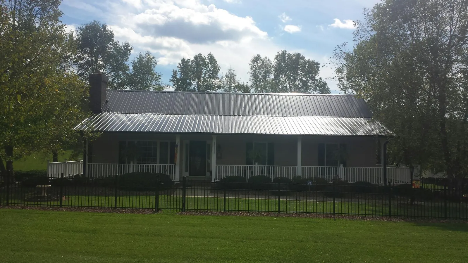 Gray metal roof on a brick ranch with a full width front porch — Gutter Guard Installation work by our crew in Nehawka