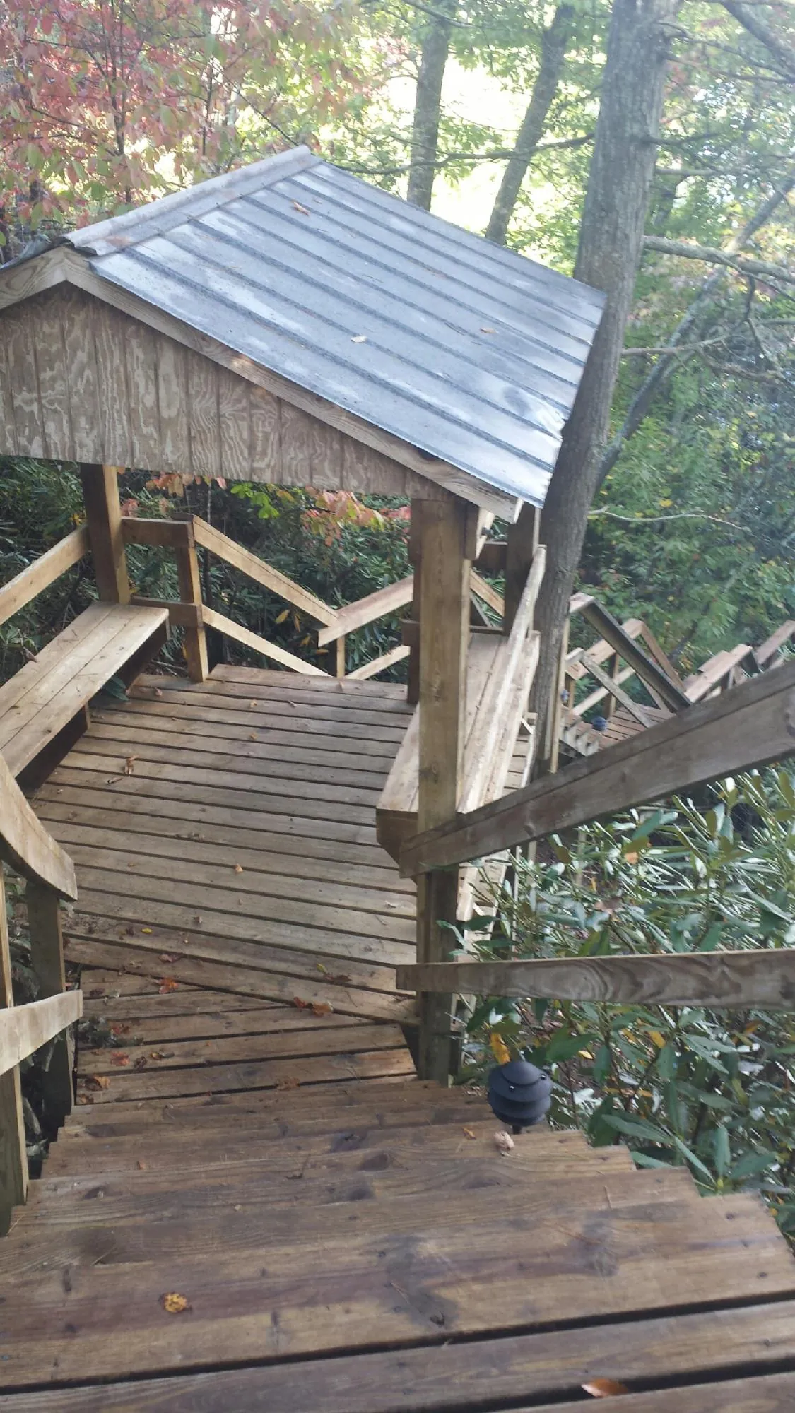 Metal roofed shelter over wooden steps on a wooded walkway — Skylight Repair & Installation work by our crew in Nehawka
