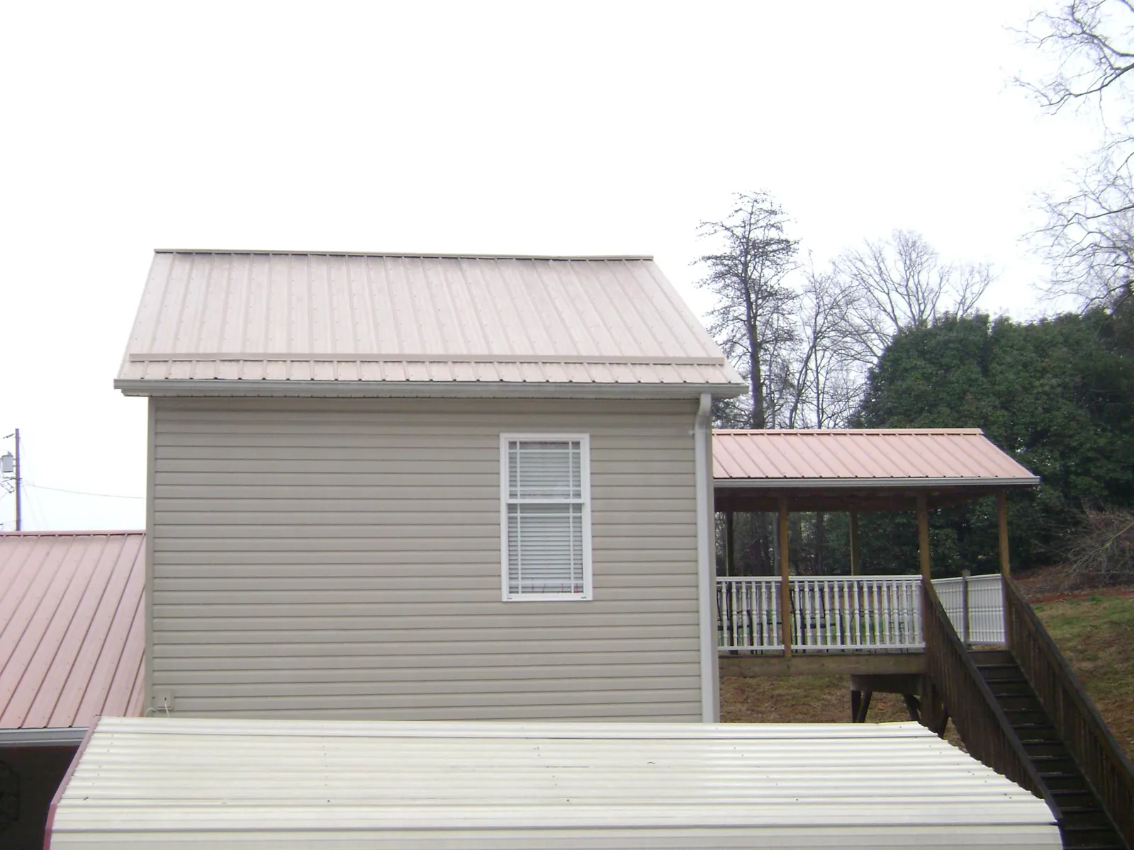 Tan metal roofs on a two story addition and attached porch, from a Roof Replacement job in Nehawka