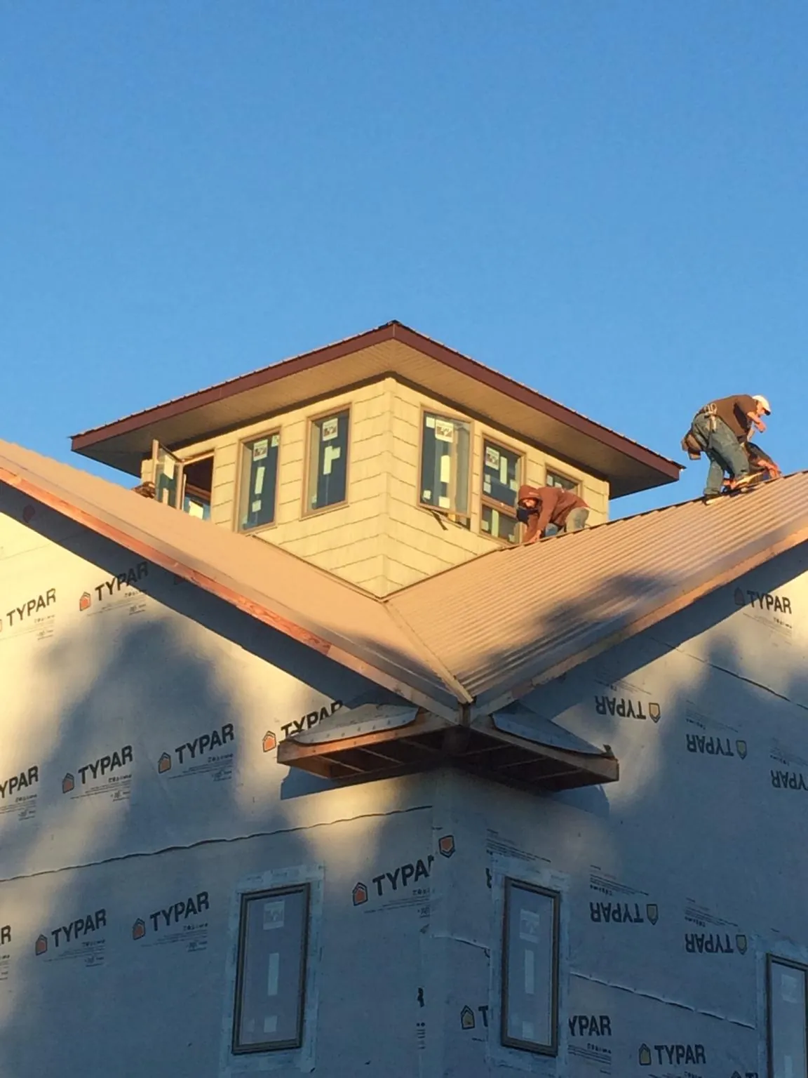Roofers working around a rooftop cupola on a new metal roof at sunset — Roof Waterproofing in Nehawka by Roofing Brothers